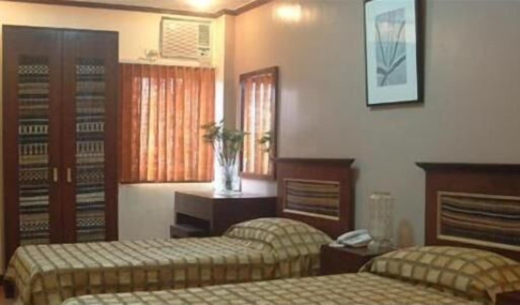 Una habitación con dos camas, un aparador, una ventana con cortinas y un cuadro en la pared.