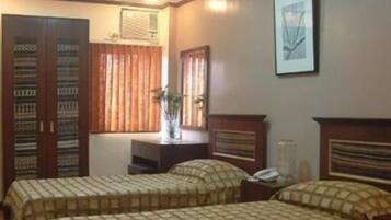 Una habitación con dos camas, un aparador, una ventana con cortinas y un cuadro en la pared.