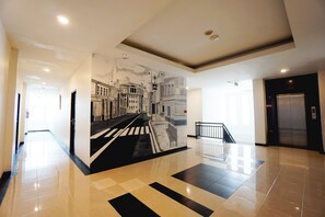A spacious lobby with a modern design, featuring a large mural of a cityscape, a staircase, and a clean, tiled floor. - Hotel 88 Mangga Besar 120 (Jakarta)