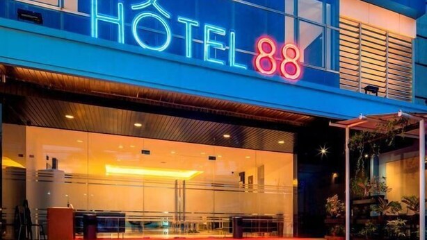 A modern hotel with a prominent neon sign reading 'HOTEL 88' and a visible entrance with a red carpet. - Hotel 88 Mangga Besar 120 (Jakarta)