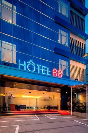 Ein modernes Hotel mit einem auffälligen Neonzeichen, das 'HOTEL 88' zeigt, und einem Eingang mit rotem Teppich.