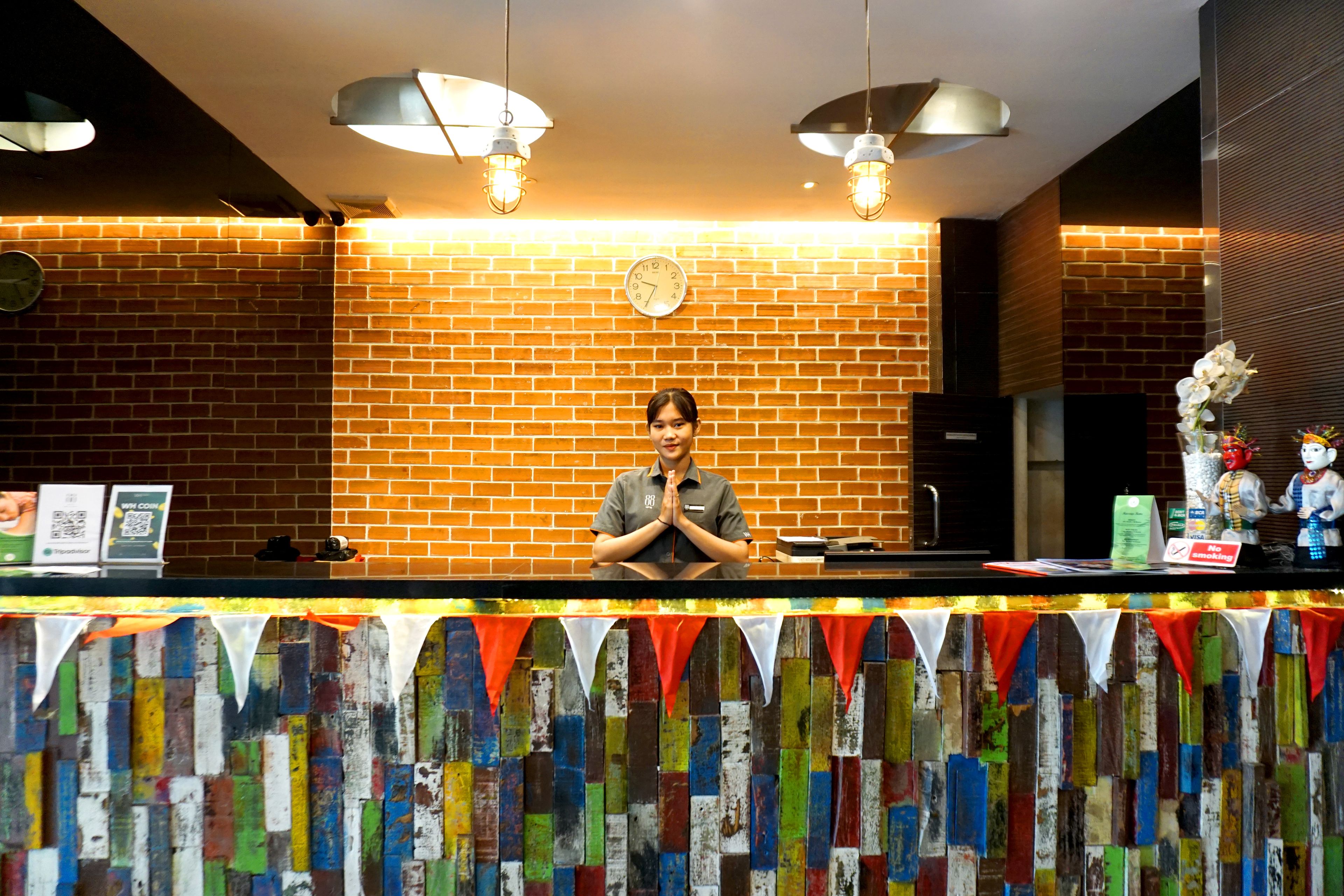 A hotel reception area with a brick wall, a clock, and a counter with various items.