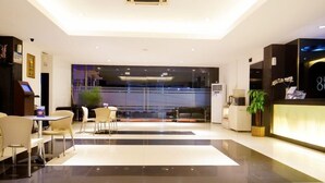 A modern hotel lobby with a reception desk, seating area, and a large window. - Hotel 88 Mangga Besar 120 (Jakarta)