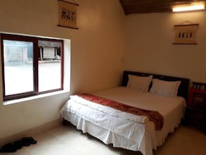 Un dormitorio con cama, ventana y cabecero de madera.