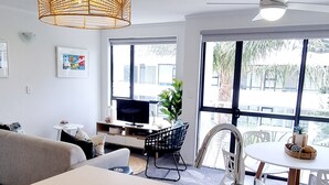A modern kitchen with a white countertop, stainless steel sink, and a hanging light fixture. - The Atrium Apartments (Tauranga)