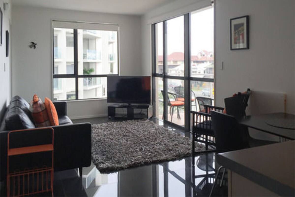 A modern living room with a sofa, TV, and dining area.