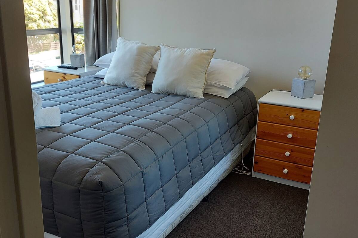 A bed with a quilted cover, a wooden nightstand with a lamp, and a small globe.