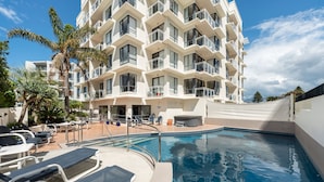 A modern hotel with a swimming pool, sun loungers, and palm trees. - The Atrium Apartments (Tauranga)