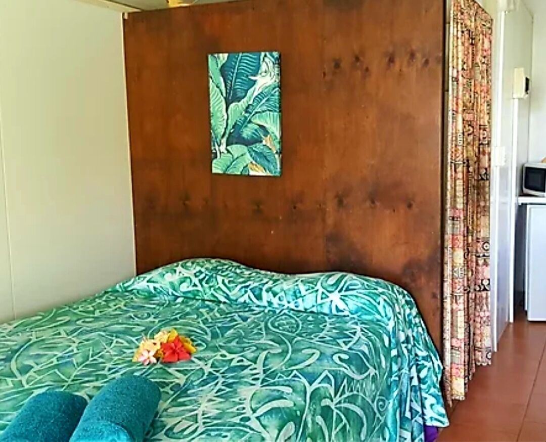Una habitación con una cama, cabecera de madera, un cuadro y una cortina.