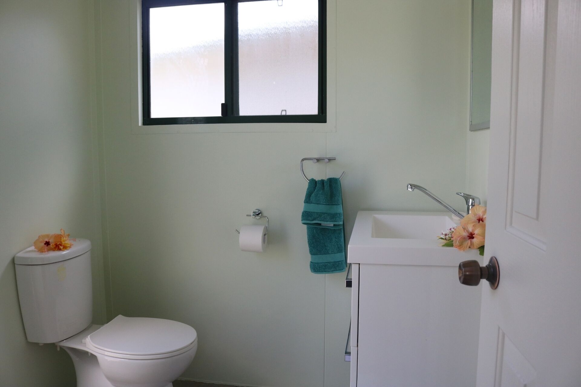 A small bathroom with a toilet, sink, and window.