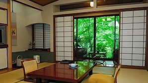 Une pièce de style japonais traditionnel, avec un sol recouvert de tatamis, une table basse et des portes coulissantes en papier de riz (shoji) donnant sur un jardin.