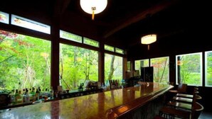 Un bar doté d’un comptoir incurvé, de grandes fenêtres et offrant une vue sur les arbres.