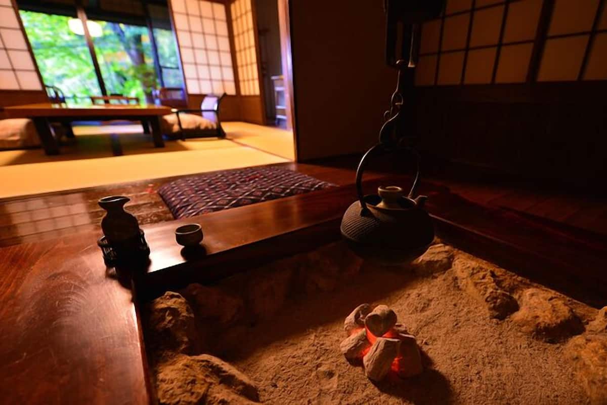 A traditional Japanese room with tatami flooring, a low table, a tea kettle, and a hanging lantern.