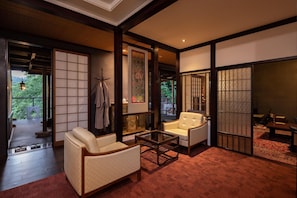 Relax in a serene space with a sofa and table, surrounded by traditional Japanese design elements and a tranquil garden view.