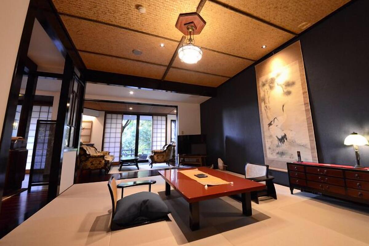 A traditional Japanese-style room with tatami flooring, a low table, and a sliding door leading to a balcony.