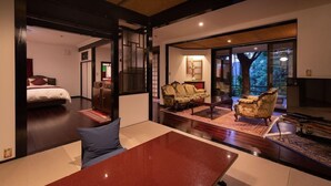 A modern hotel room with a bed, seating area, and a large window offering a view of the outdoors. - Sanso Tensui (Hita)