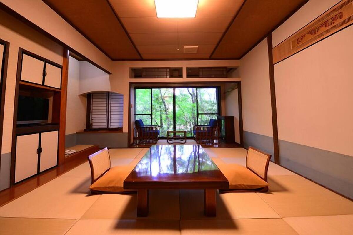 Ein traditioneller japanischer Raum mit Tatami-Bodenbelag, einem niedrigen Tisch und verschiebbaren Türen.