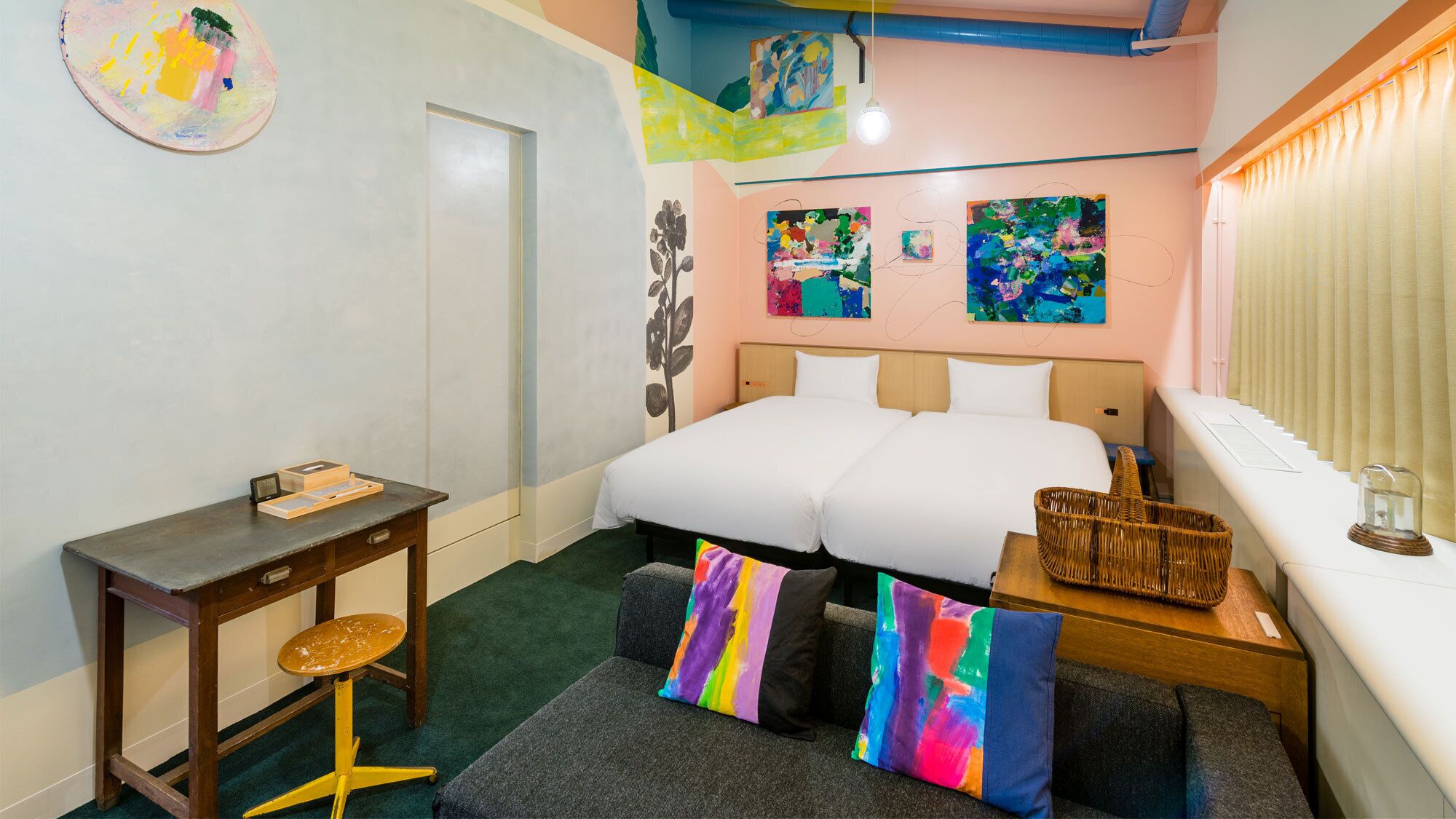 A bedroom with a bed, a desk, a chair, and two colorful pillows.