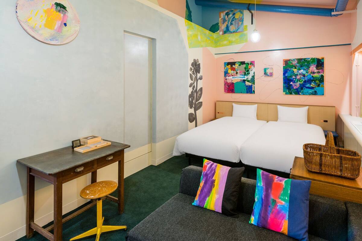 Un dormitorio con cama, escritorio, silla y dos almohadas coloridas.