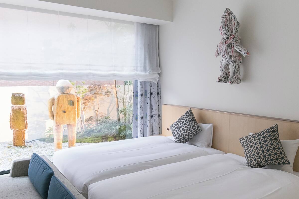 Habitación de hotel con una cama grande, un sofá, vistas al exterior y una decoración en la pared.