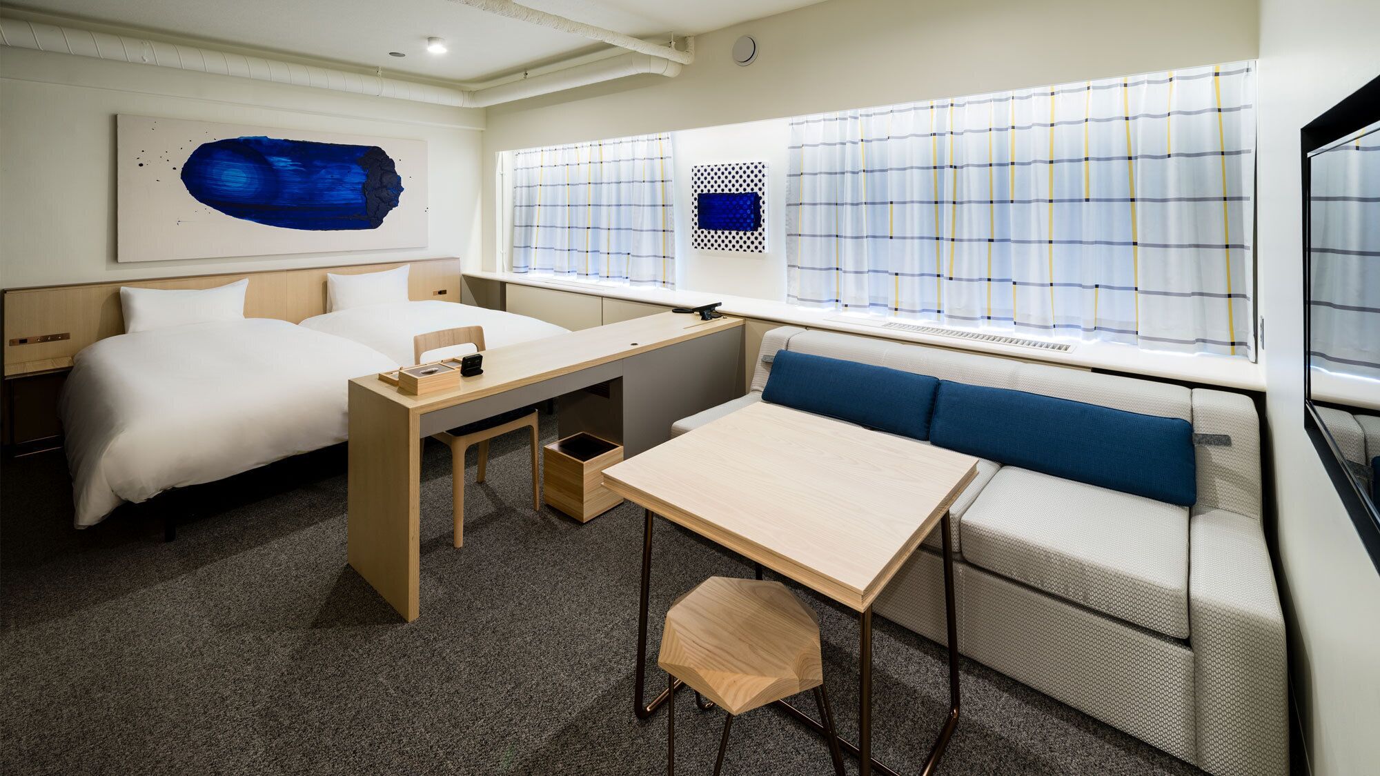 A modern hotel room with a bed, desk, and seating area.