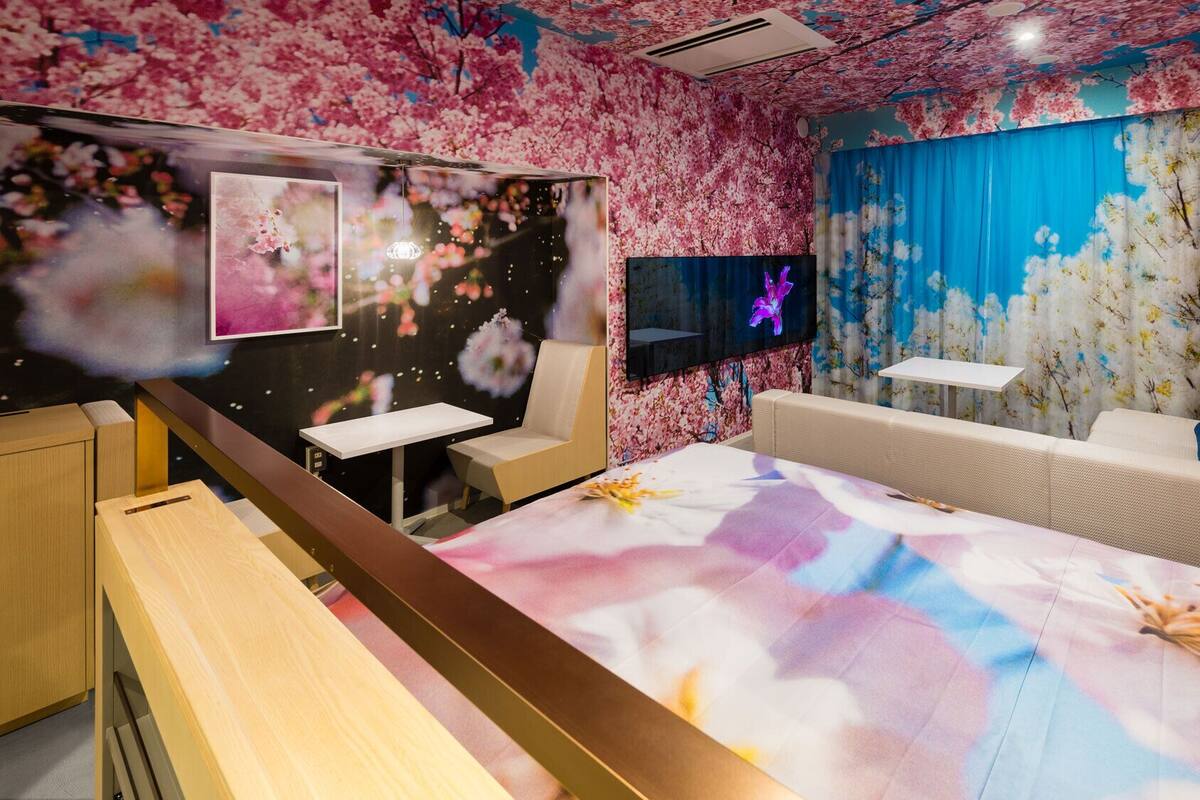 Una habitación con papel tapiz de flores de cerezo, un televisor de pantalla plana, un sofá y una mesa.