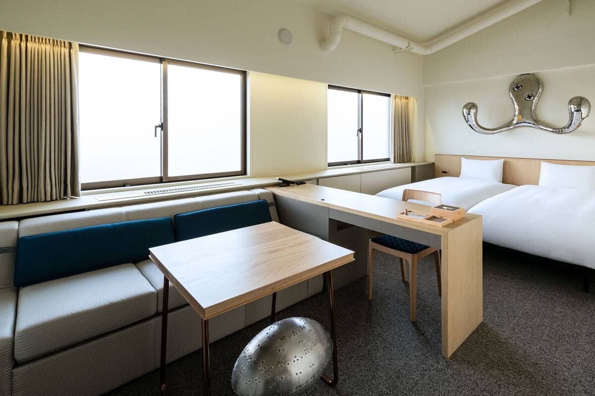Una habitación de hotel con una cama, un escritorio, una silla, un sofá y una ventana.