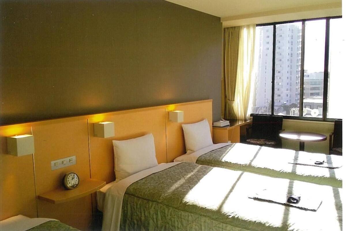 A hotel room with a large bed, bedside tables, a desk, and a chair.