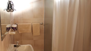 A bathroom with a sink, two towels, a shower curtain, and a mirror with a towel rack. - Flinders Ranges Motel (Quorn)