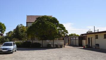 A parking lot with a building in the background, a tree, and a car.