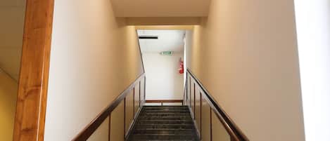 A marble staircase with wooden handrails and a white wall.
