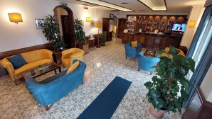 Eine Lobby mit Barbereich, Sofas und Topfpflanzen.
