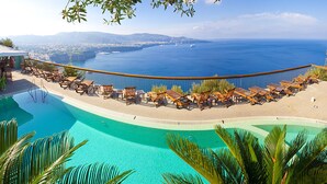 A poolside area with lounge chairs and a view of the sea. - Hotel Mega Mare (Vico Equense)