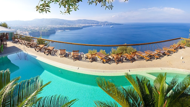 Ein Poolbereich mit Liegestühlen und Meerblick.
