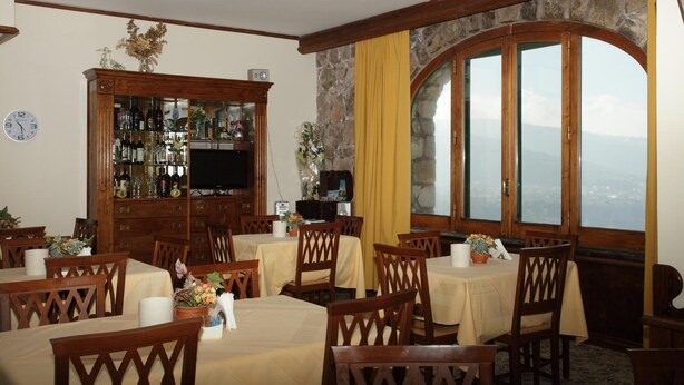A dining area with tables and chairs, a bar with bottles, and a large window with a view. - Hotel Mega Mare (Vico Equense)