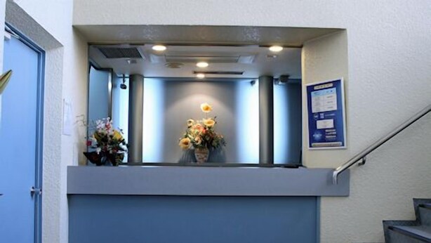 A reception area with a desk, a vase with flowers, and a staircase. - Karato Central Hotel (Shimonoseki)