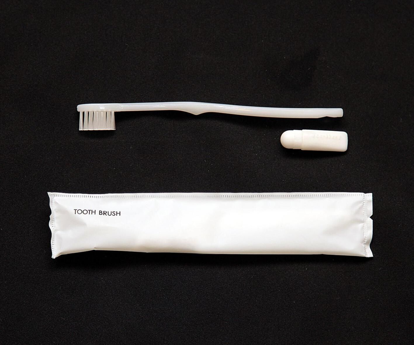 A white toothbrush, a toothbrush head, and a toothbrush case.