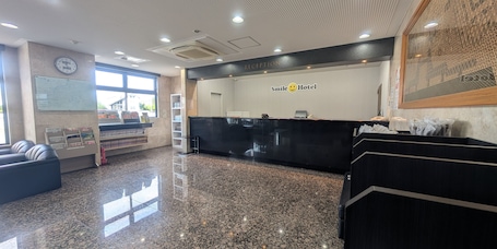 A reception area with a reception desk, a clock, and a wall-mounted sign that reads "Smile Hotel."