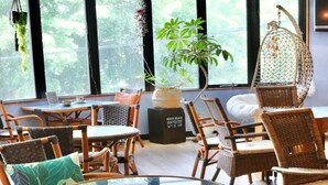 A cozy cafe with wicker furniture, large windows, and hanging plants. - Pension Moon Villa (Onna)