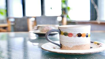 A ceramic mug with a colorful stripe on a saucer, placed on a glass table.