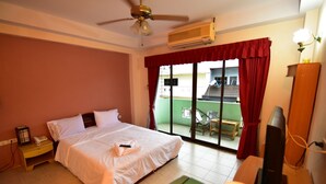 A hotel room with a bed, a bedside telephone, an air conditioning unit, a television, and a view of the outside balcony. - Billabong Hotel (Pattaya)