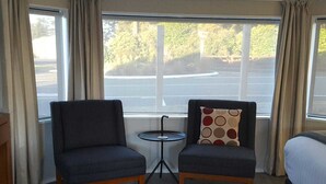 A room with two armchairs, a small round table, and a bed. - Ohakune Central Motels (Ohakune)