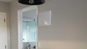 A modern kitchen with a white countertop, a sink, and a mirror. There is a white dining table with four chairs. - Ohakune Central Motels (Ohakune)
