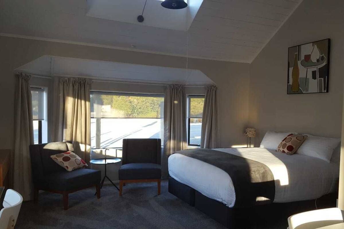 A hotel room with a large bed, a desk, a chair, and a small table.