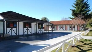 A building with a covered swimming pool and a separate building with a red roof. - Ohakune Central Motels (Ohakune)