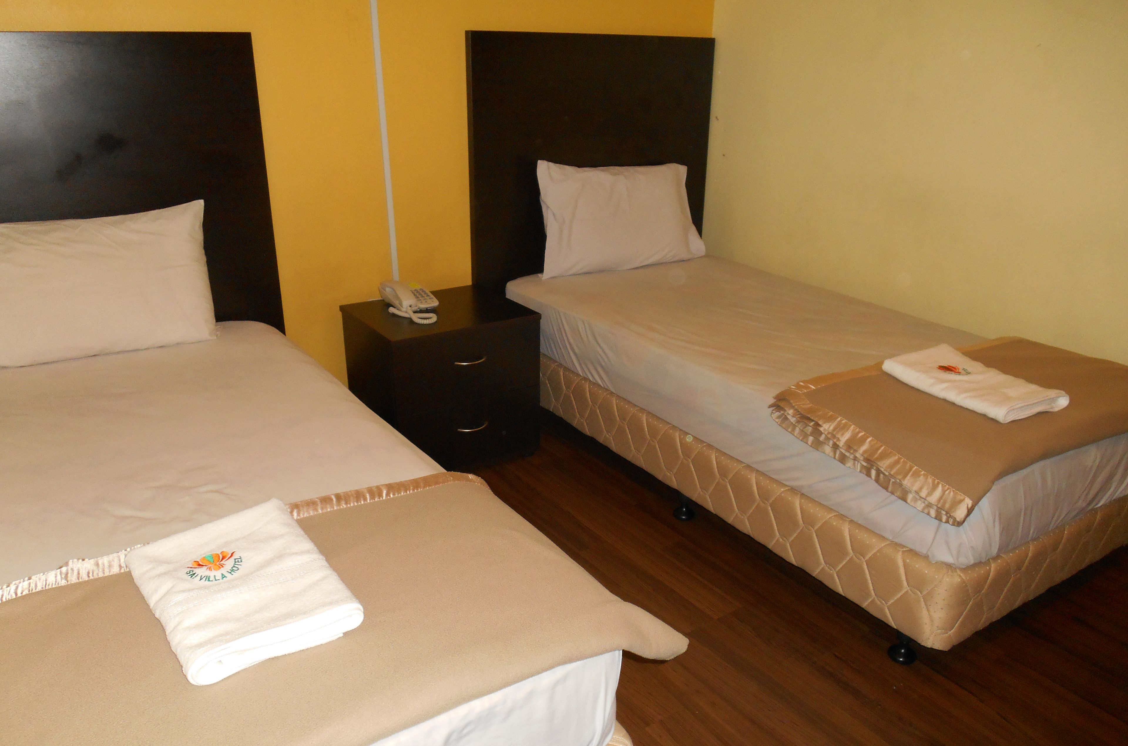 Two single beds with headboards, a bedside table with a phone, and a towel on the floor.