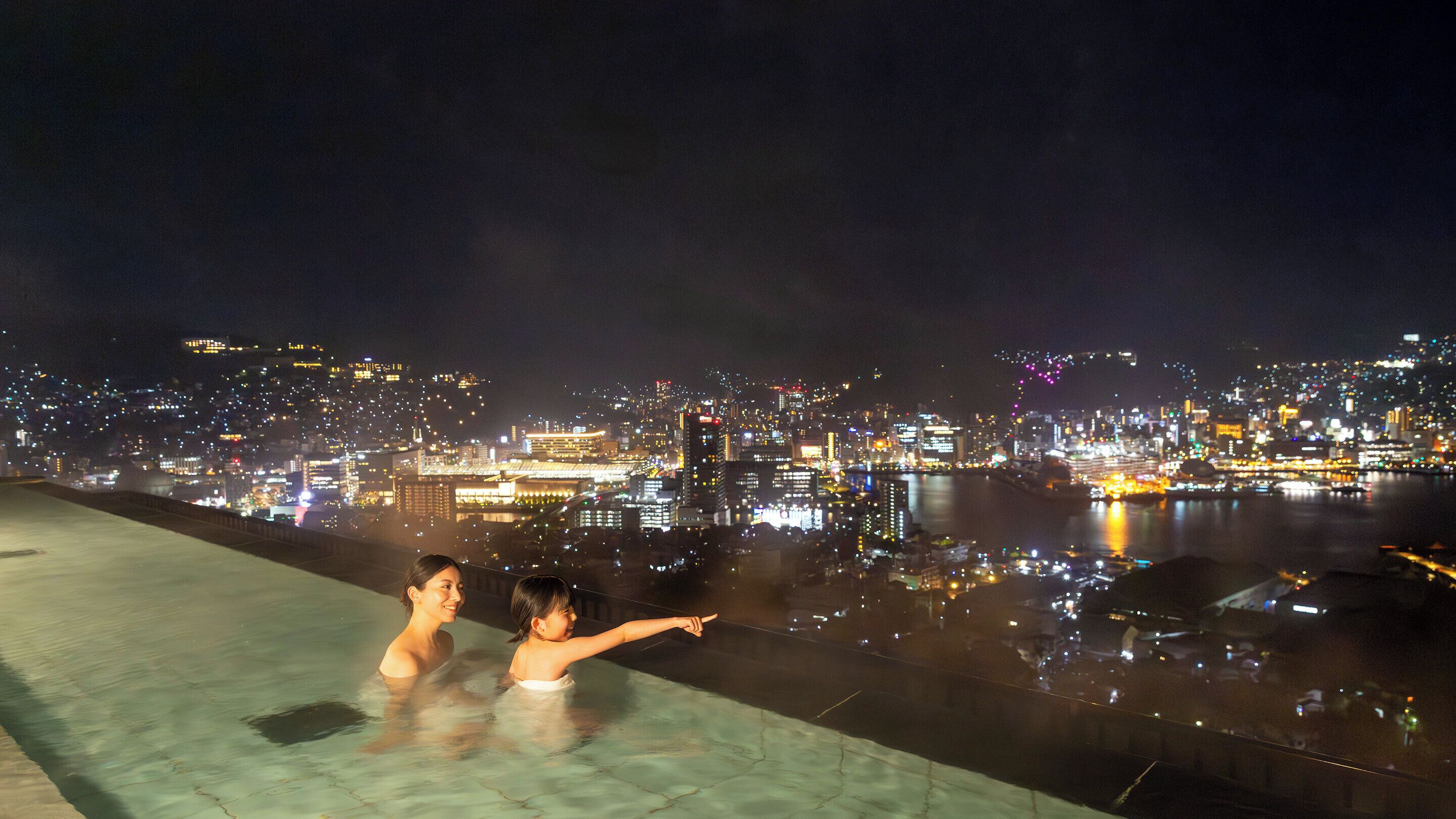 A nighttime cityscape with a waterfront view.