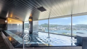 En modern inomhuspool med utsikt över staden, stora fönster och ett högt tak.