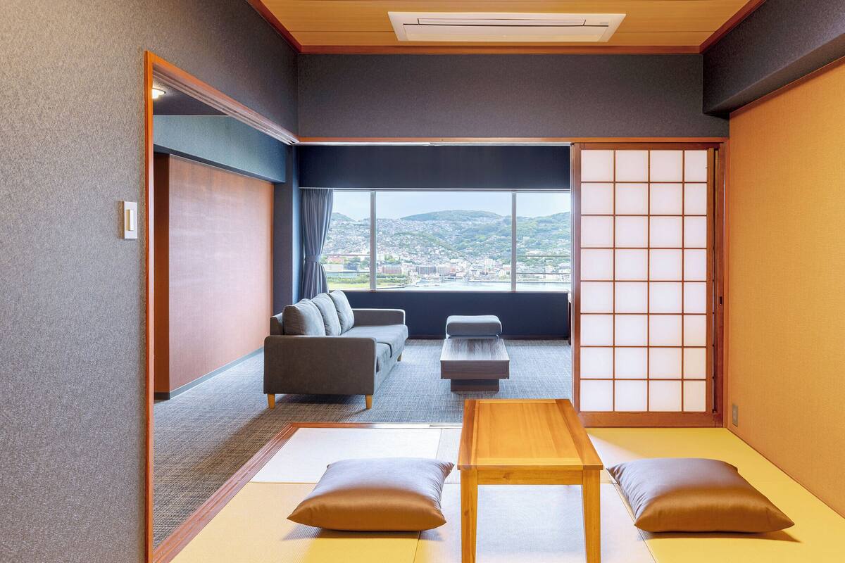 A traditional Japanese room with tatami flooring, a low wooden table, cushions, and a sliding shoji screen.