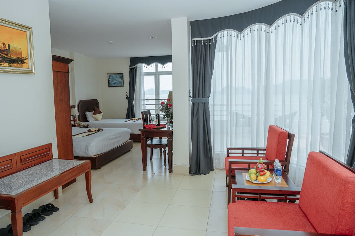 A hotel room with a bed, a desk, a dining table with fruit, and a sofa.